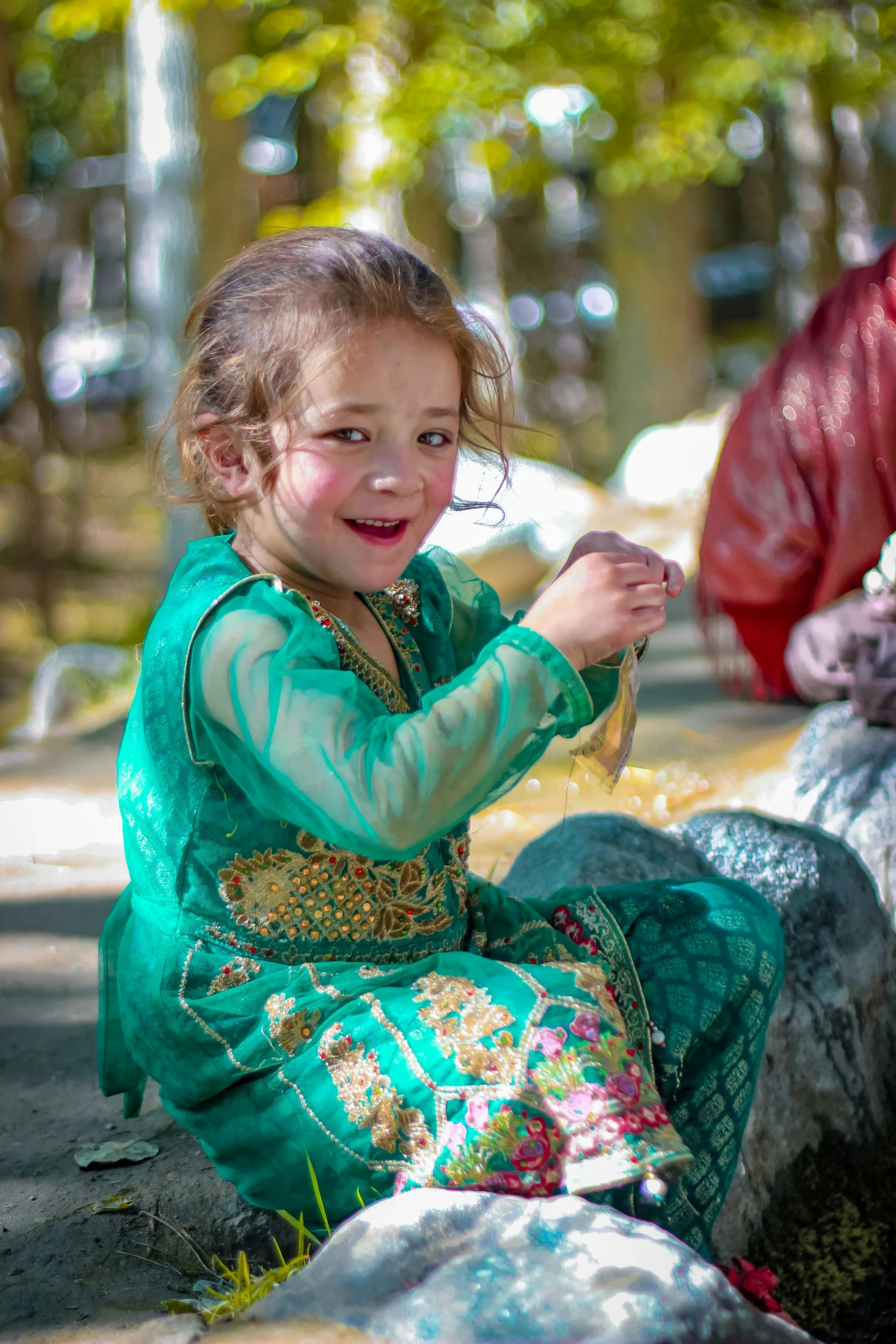  with bead and green dress sitting on rock outdoors