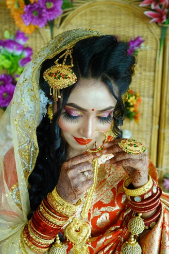 a woman in a red and gold bridal veil holding gold jewelry