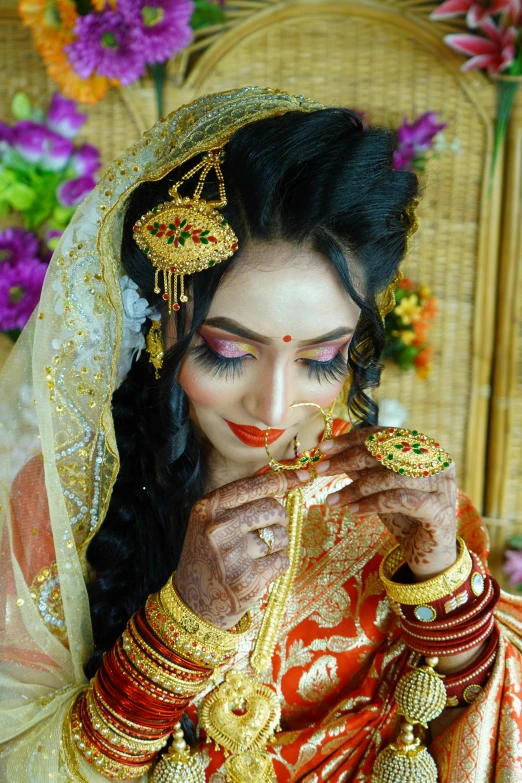 a woman in a red and gold bridal veil holding gold jewelry