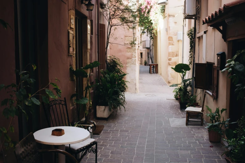 a narrow street with tables and chairs along side building