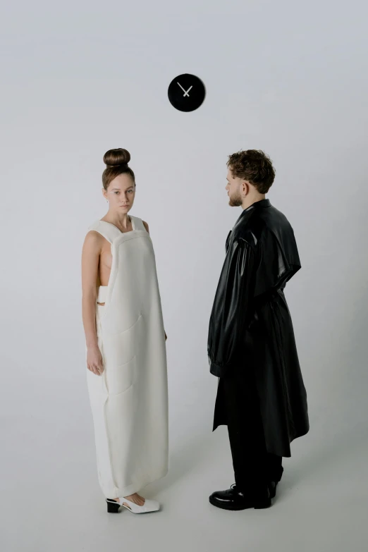 man and woman wearing black robes standing in front of white wall