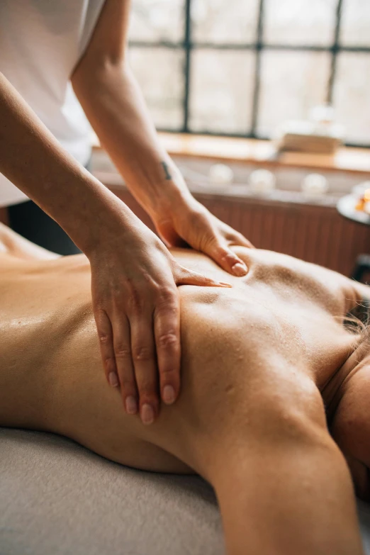 a woman laying on top of a man getting a back massage