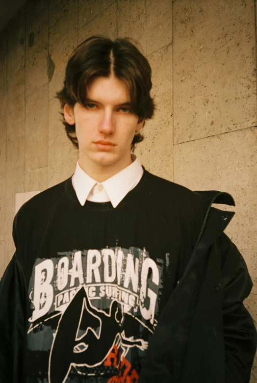 a young man wearing a black and white shirt with his hands folded up