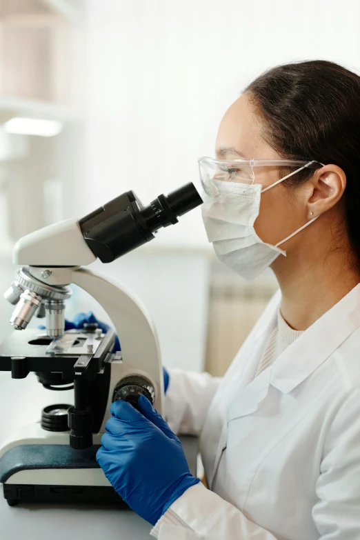 a female scientist in white lab coat using microscope