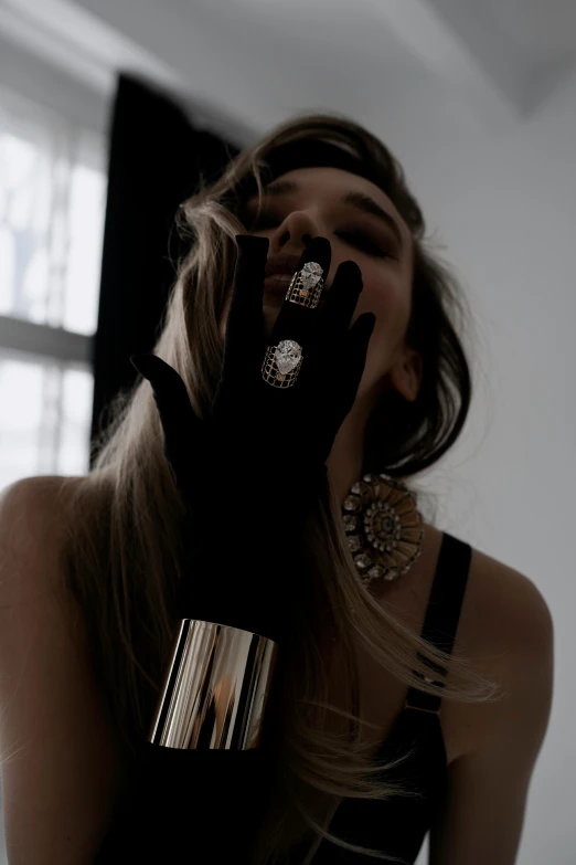 a girl wearing jewelry poses in front of a window