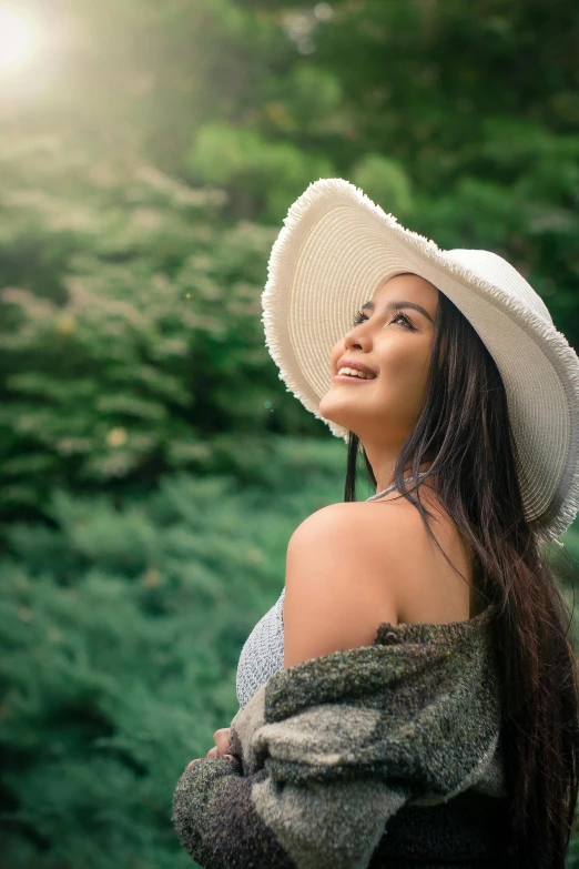 a girl wearing a white hat and posing in front of a field