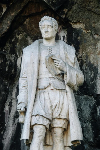 a statue standing next to a stone wall