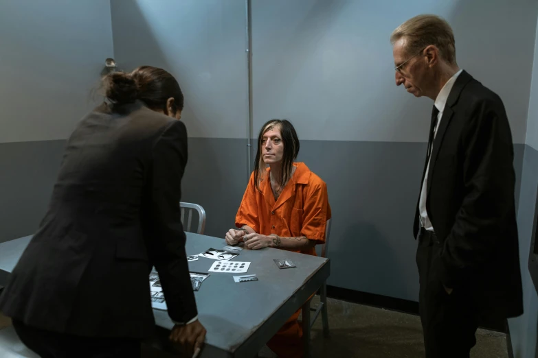 people sitting around a table while one man in orange is listening