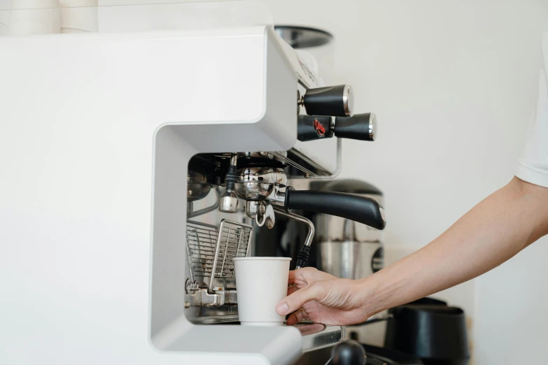 person holding a cup and filling up the cappuccino machine