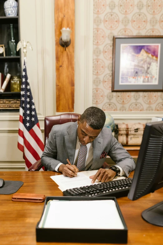 a man in business attire writing in his desk