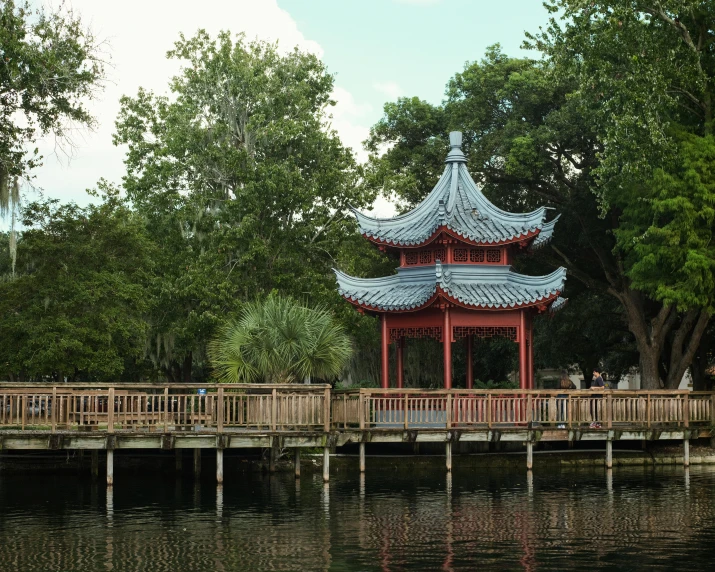 a scenic chinese building sitting on a wooden bridge over water