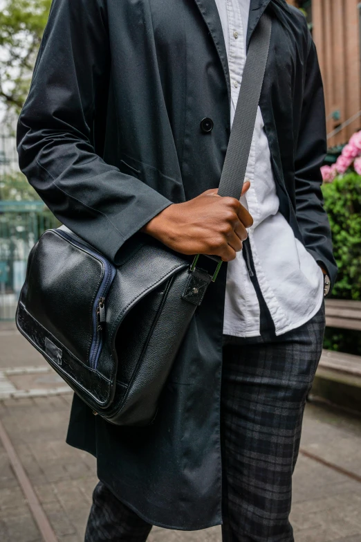 a man wearing a coat carrying a black handbag