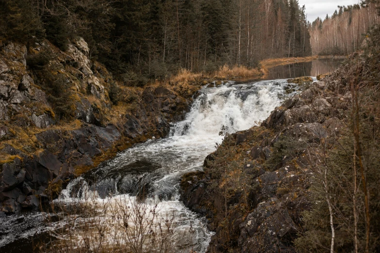 a small waterfall is in between some rocks and trees