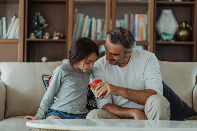 a man and  are sitting on a couch, brushing their teeth