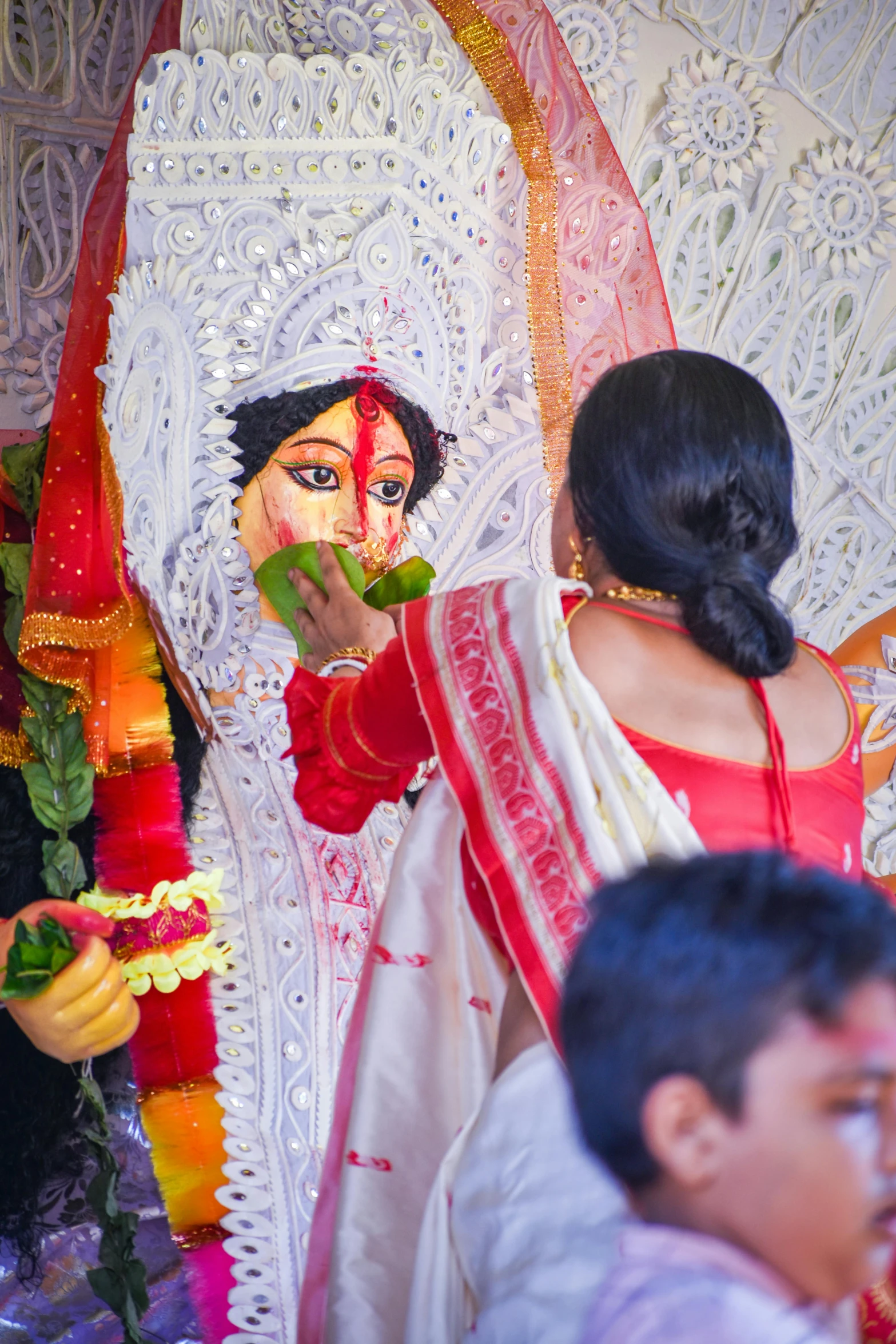 a woman holding a flower near a face painted on a doll