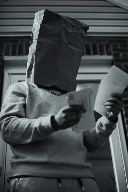 a person wearing a paper bag on their head with some books in front of them