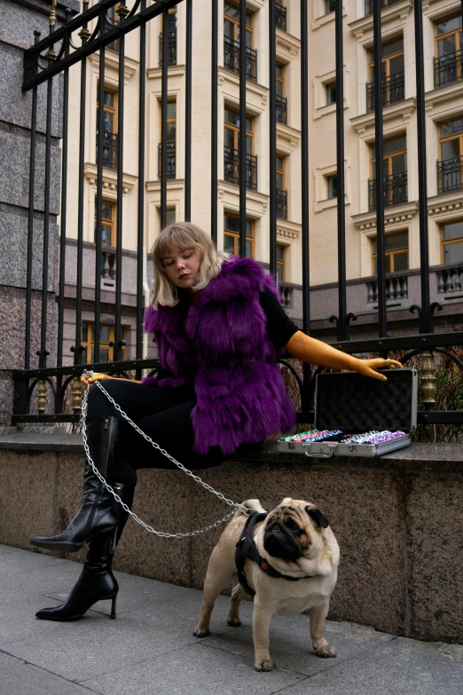 the woman sits on the railing next to her dog, and stares at her purse