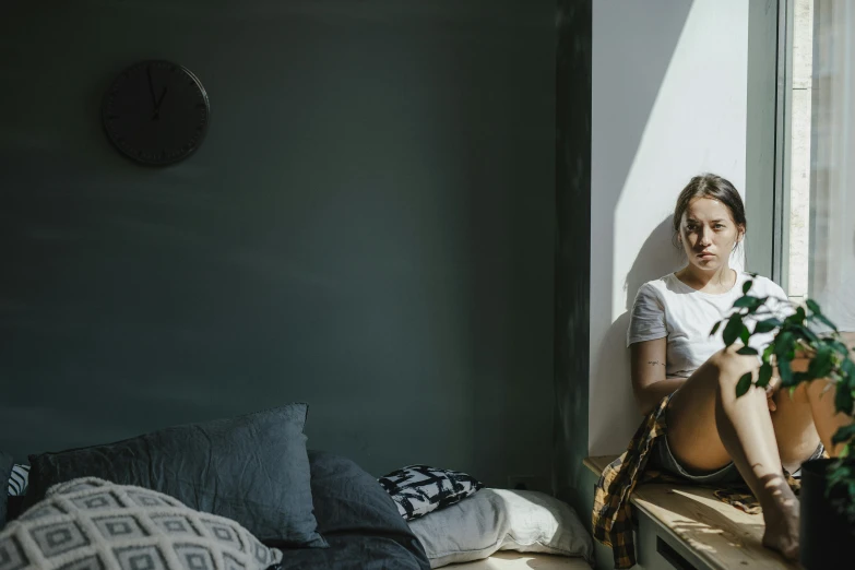 a woman sitting on a window sill staring outside