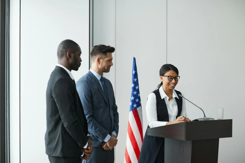 two men and one woman are at a podium