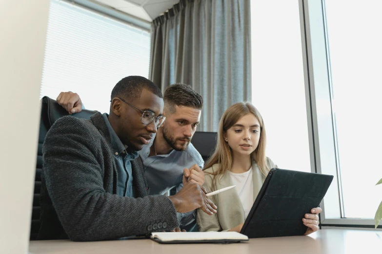 a man and two women looking at soing on a laptop