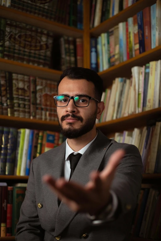 a man in a suit and tie stands behind a bookcase