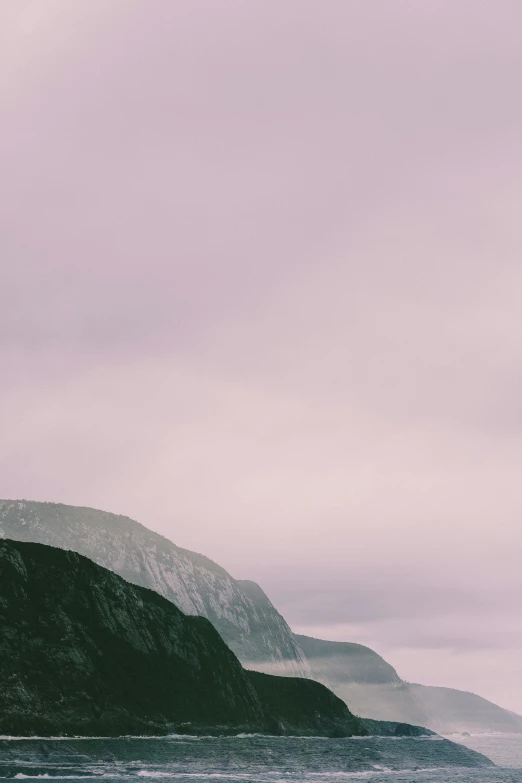 the silhouette of a mountain in foggy weather