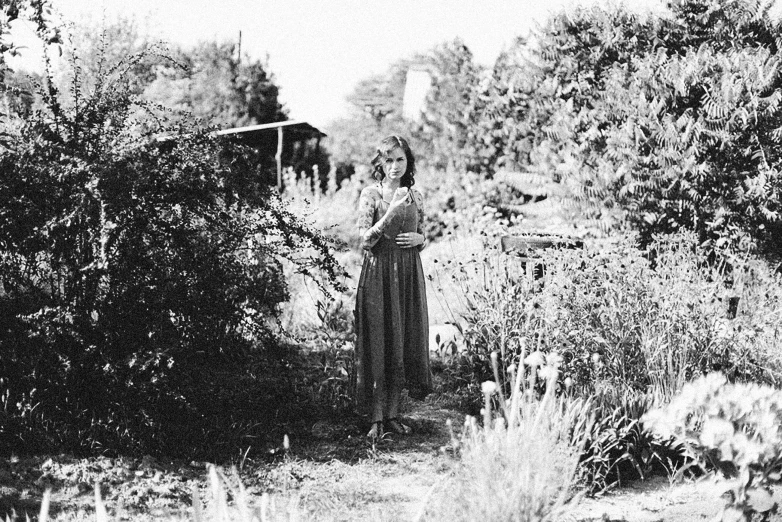 woman standing in an overgrown field, near tree's