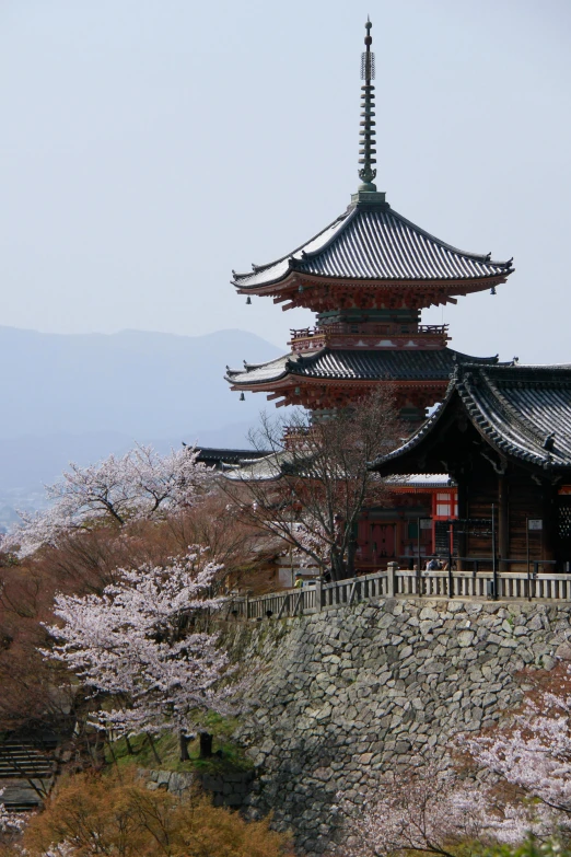 a pagoda stands tall over a wall covered in trees