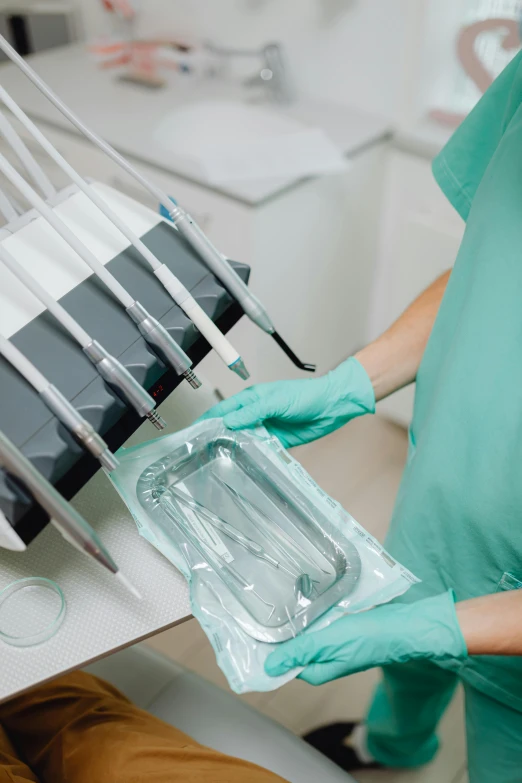 a nurse in scrubs holding several dental utensils