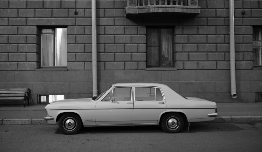 black and white pograph of a old car parked outside of a building