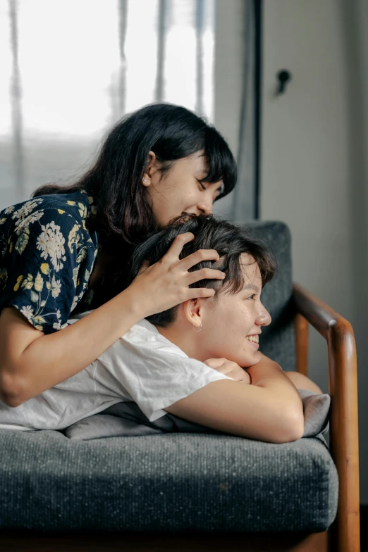 a woman sitting on top of a couch getting her hair combed