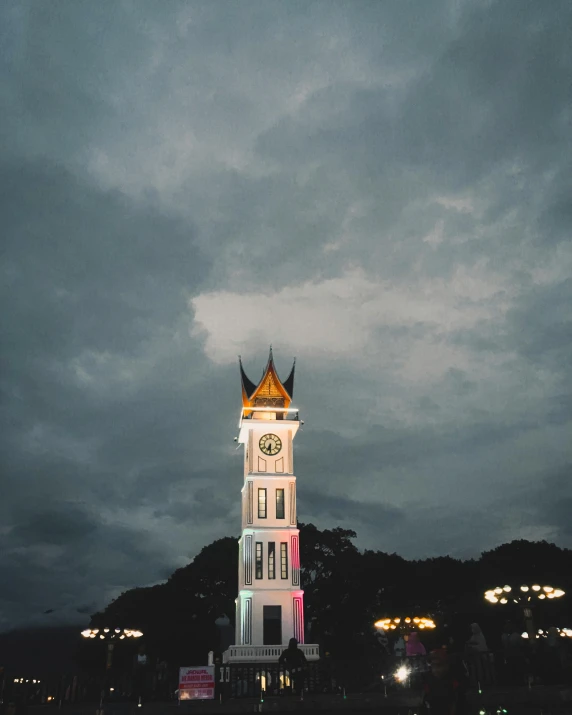 the white clock tower is lit up and has many clocks on it