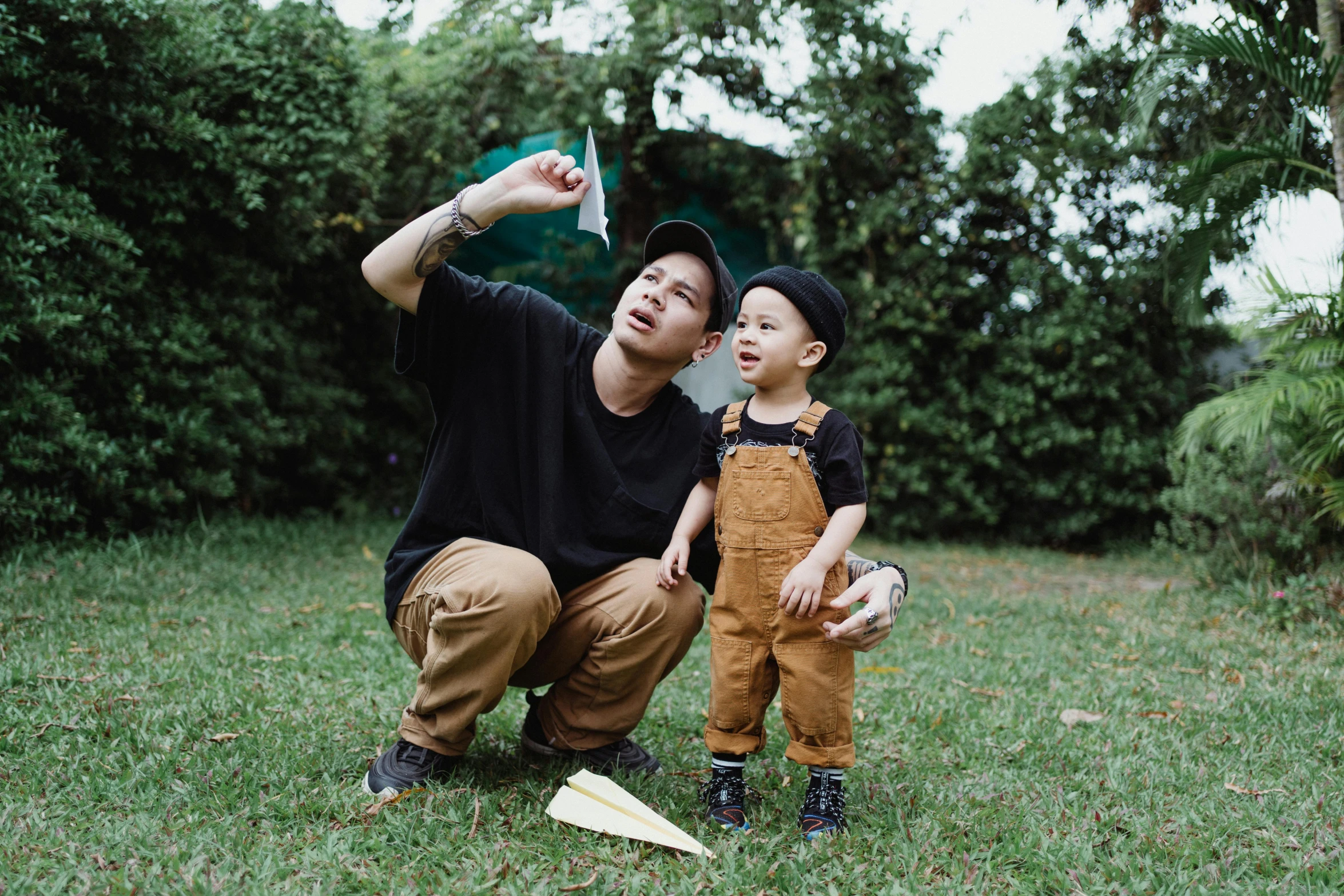 man kneeling down holding young child near flying disc in field