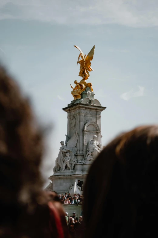 a statue of a golden angel sits above a crowd of people