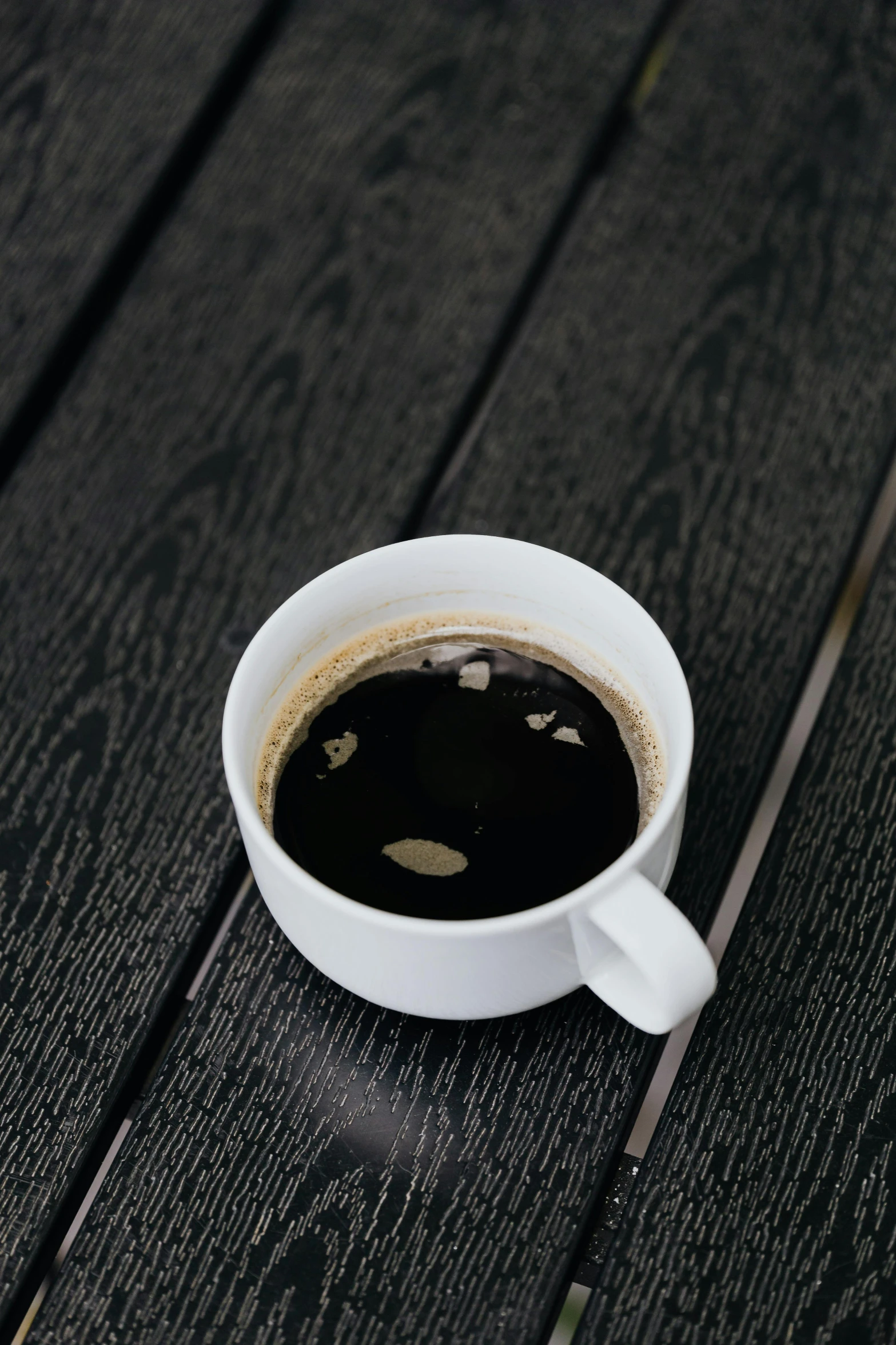 a white cup filled with liquid sitting on top of a wooden table