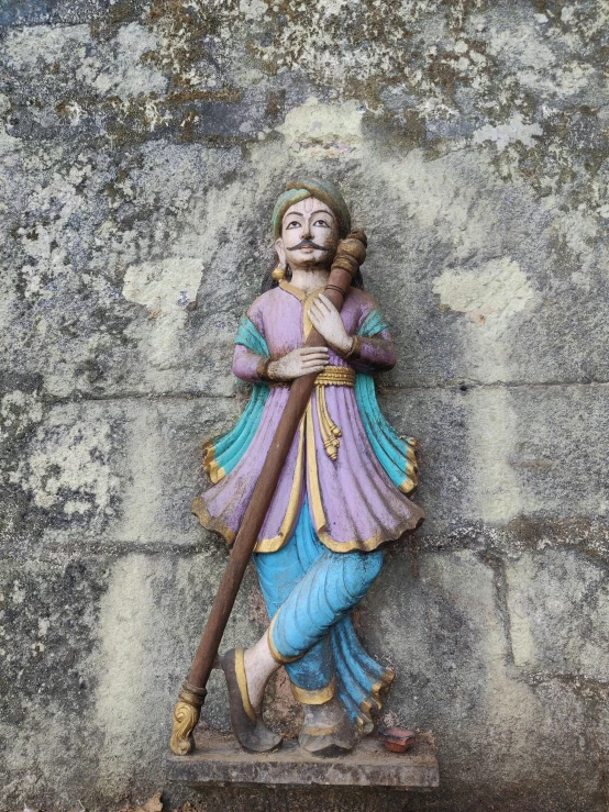 a small statue is sitting by a wall