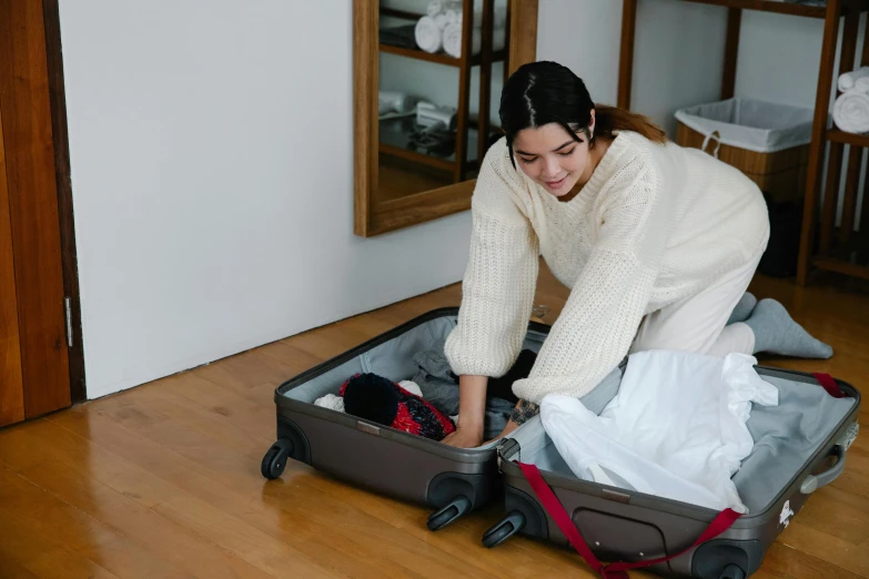 a woman packing up clothes on a floor