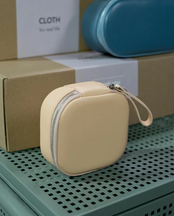 a tan leather cosmetic bag on a metal surface