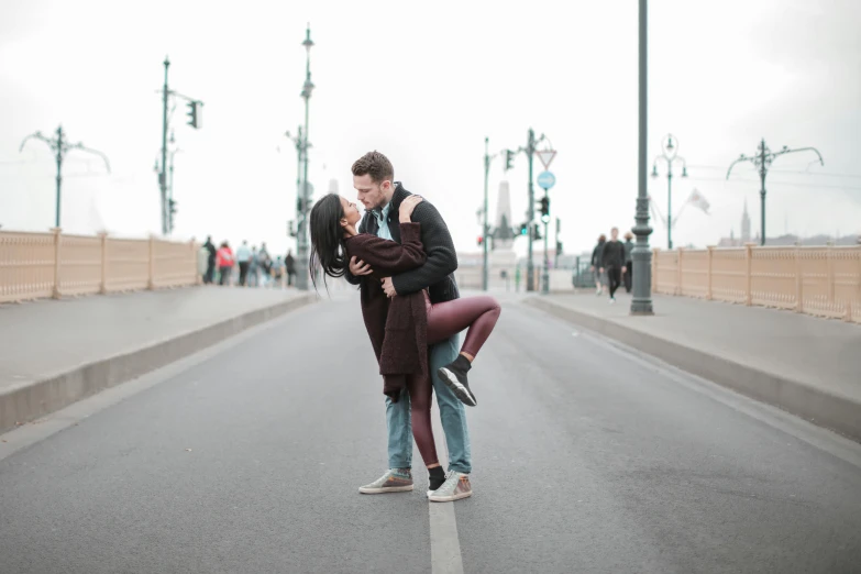 man and woman hugging each other in the middle of the street