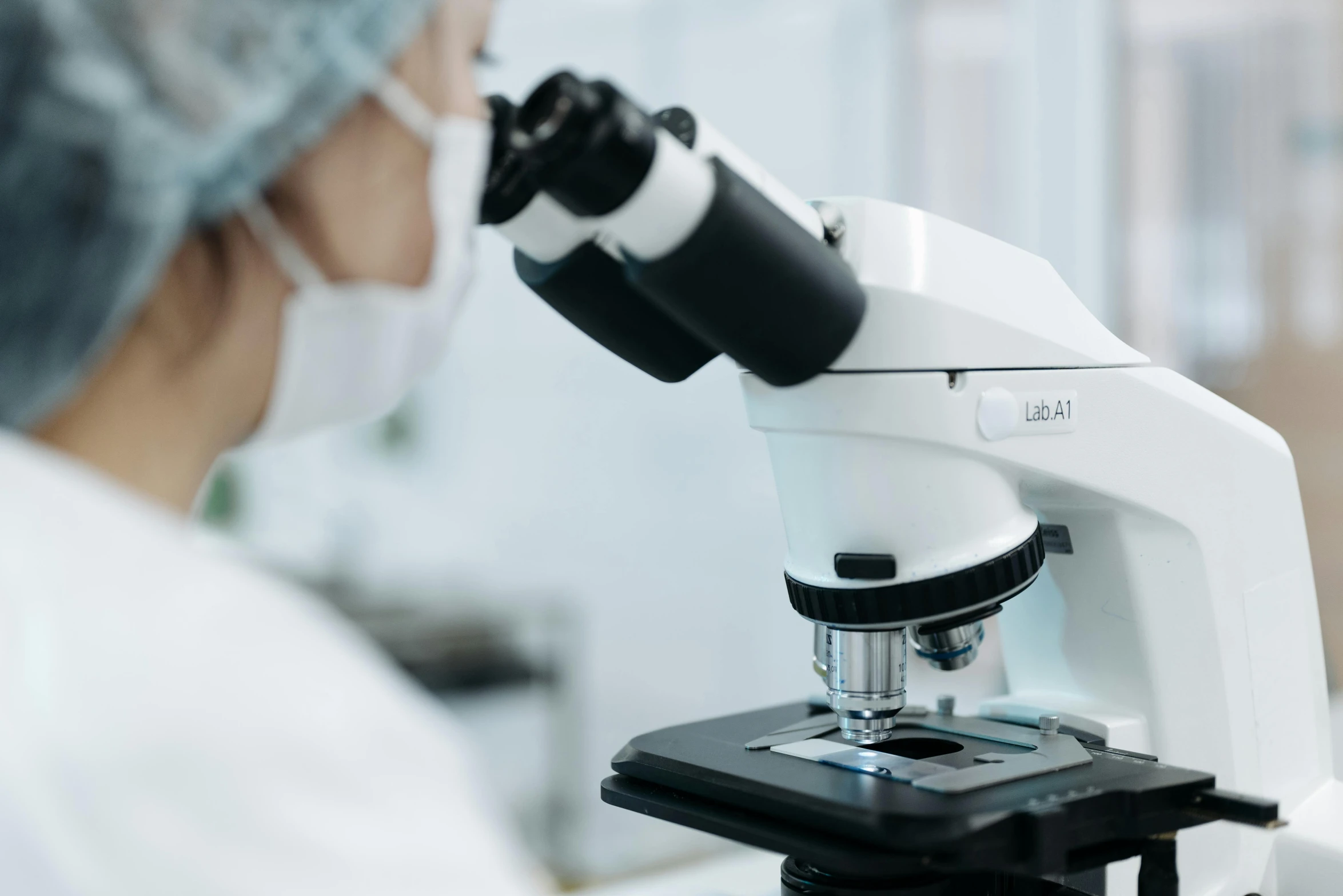 a woman looking into a microscope with the word ugl on it