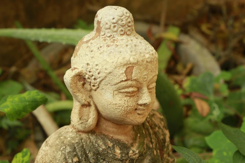 there is an old buddha statue sitting in the garden