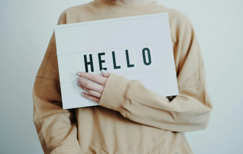 a woman holding a sign reading hello