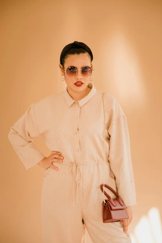 a woman wearing a white jumpsuit holding a purse