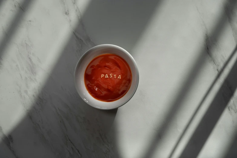 a bowl filled with sauce on top of a white table