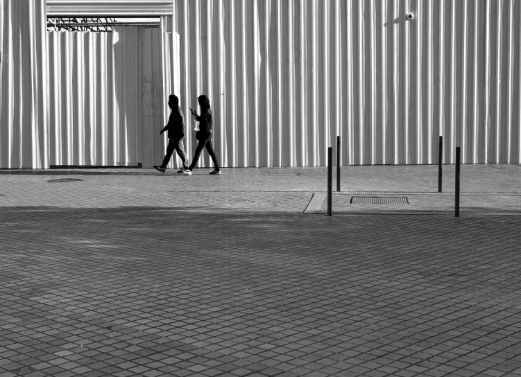 two people holding hands as they walk past a building