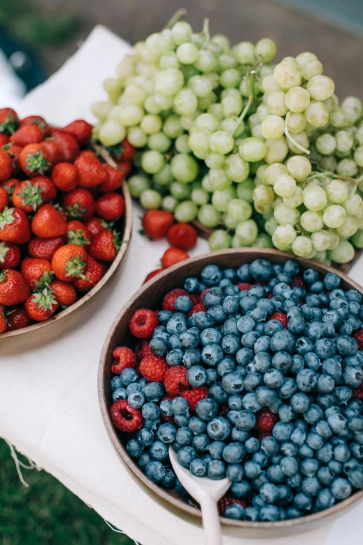 several bowls of berries and gs on top of a white table cloth