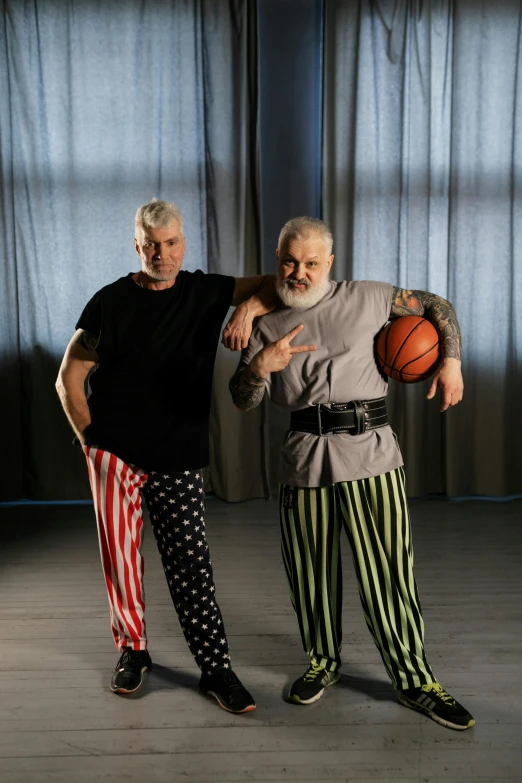 two men wearing matching clothes with basketballs