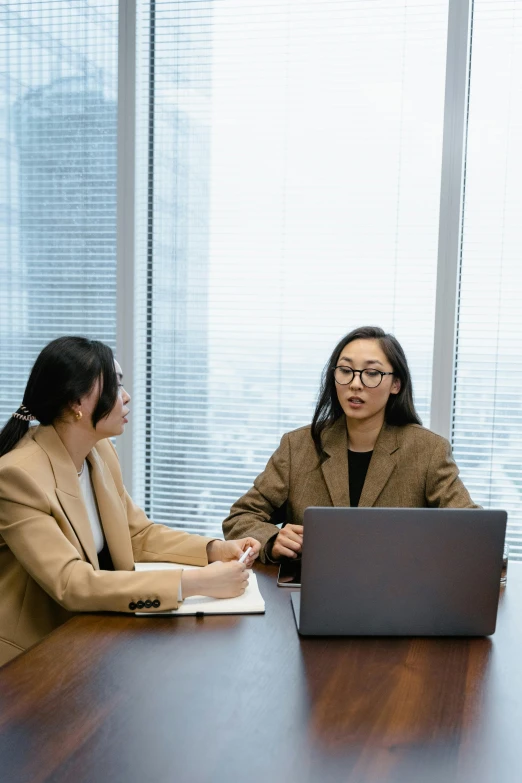 a woman is talking while two other women are seated at a conference table