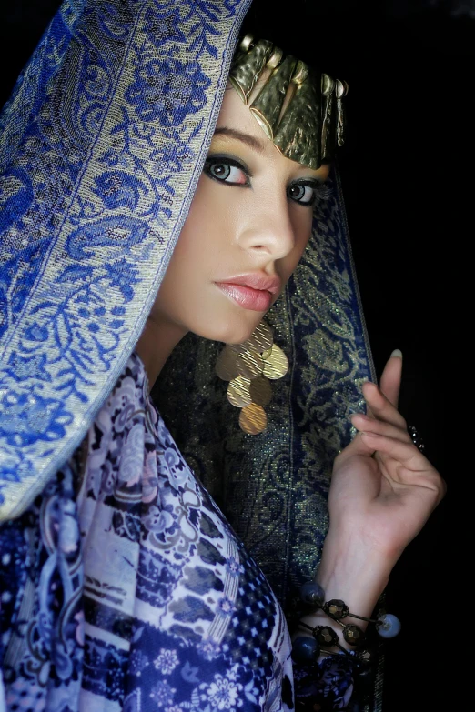 a beautiful young lady wearing jewelry and a blue headdress