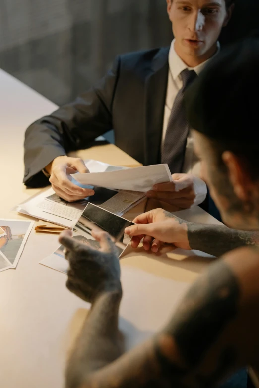 three people wearing suits sit around a table with a menu